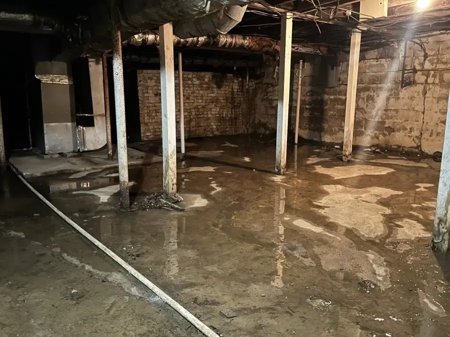 Older Queens basement with block and brick walls and standing water on the floor