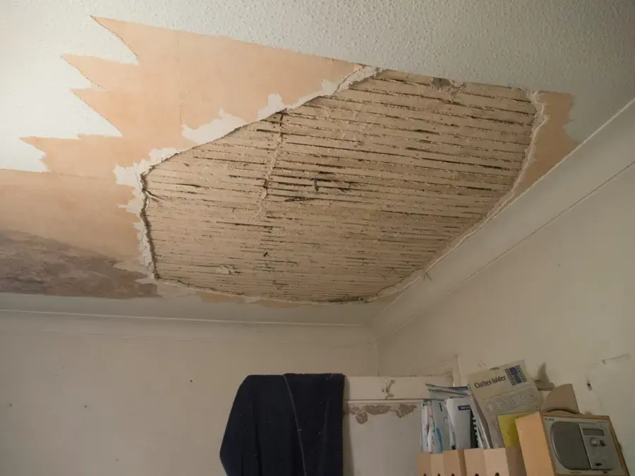 Plaster ceiling torn open by a leak from the unit above in a Jamaica apartment