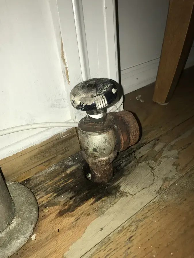 Water-stained wood floor under a leaking radiator valve in a Jamaica, NY home